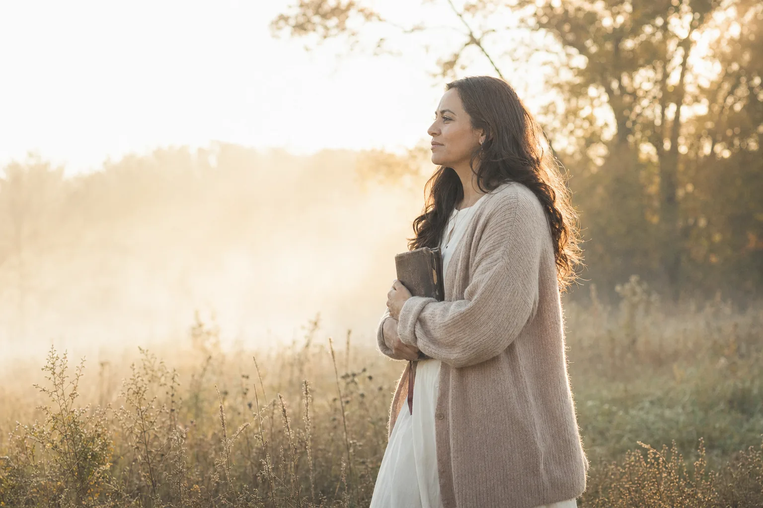 Woman holding Bible while walking through field